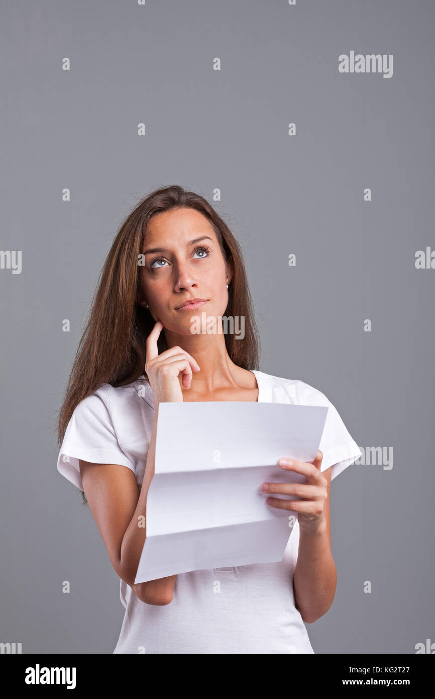 Slim donna pensando a ciò che lei ha appena letto su tale lettera documento o foglio Foto Stock