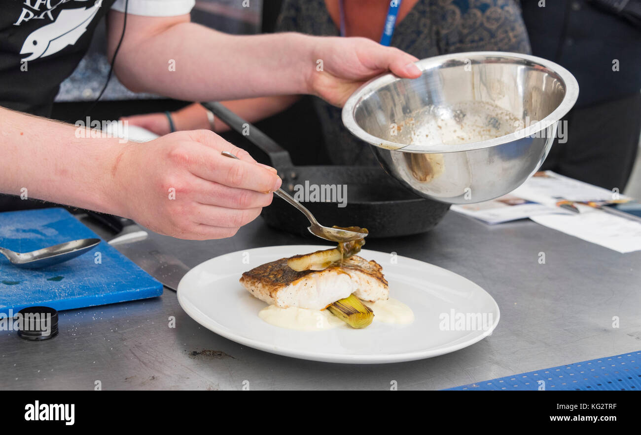 Come la parte finale del demionstration cucina lo chef serve il cibo (pesce) su una piastra. Foto Stock