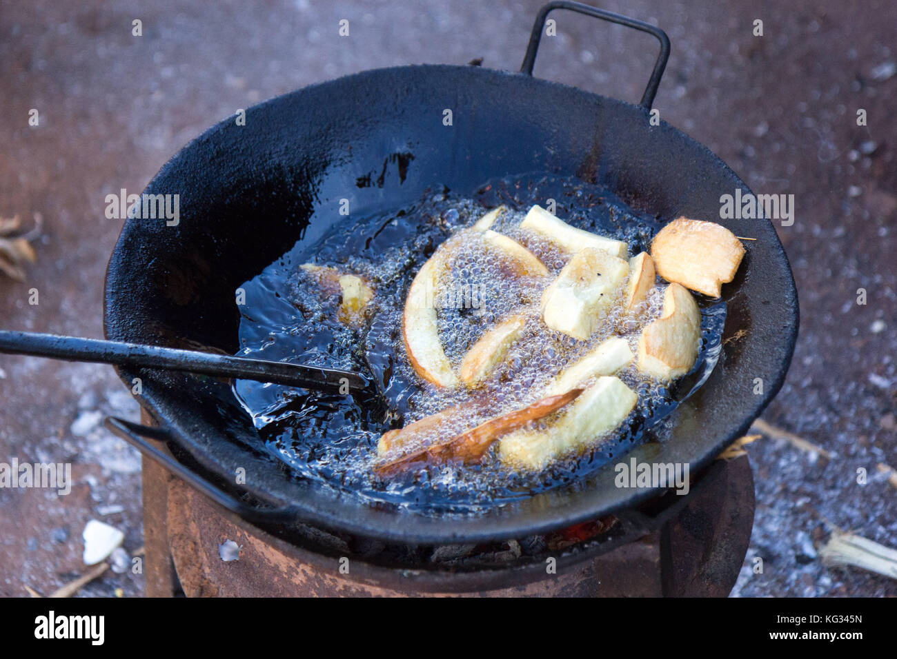 La Manioca di frittura in olio in un tegame sul fuoco stufa. Foto scattata in Najja, Uganda il 9 maggio 2017. Foto Stock