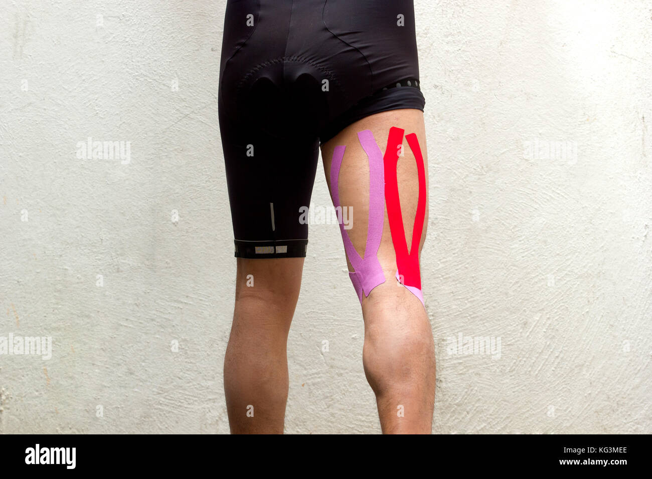 La foto in orizzontale di un ciclista maschio con kinesio taping sul suo posteriori della coscia per ridurre il dolore Foto Stock