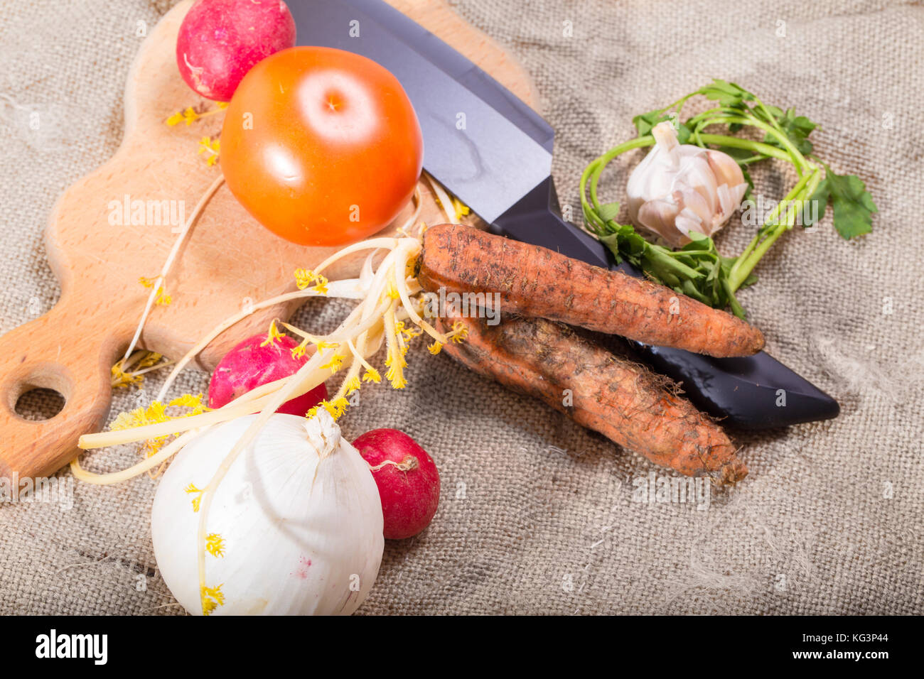 Il grezzo di verdure, il coltello e la scheda su un saccheggio. old dirty carote, cipolle, aglio, pomodoro, verdi, giardino ravanello Foto Stock