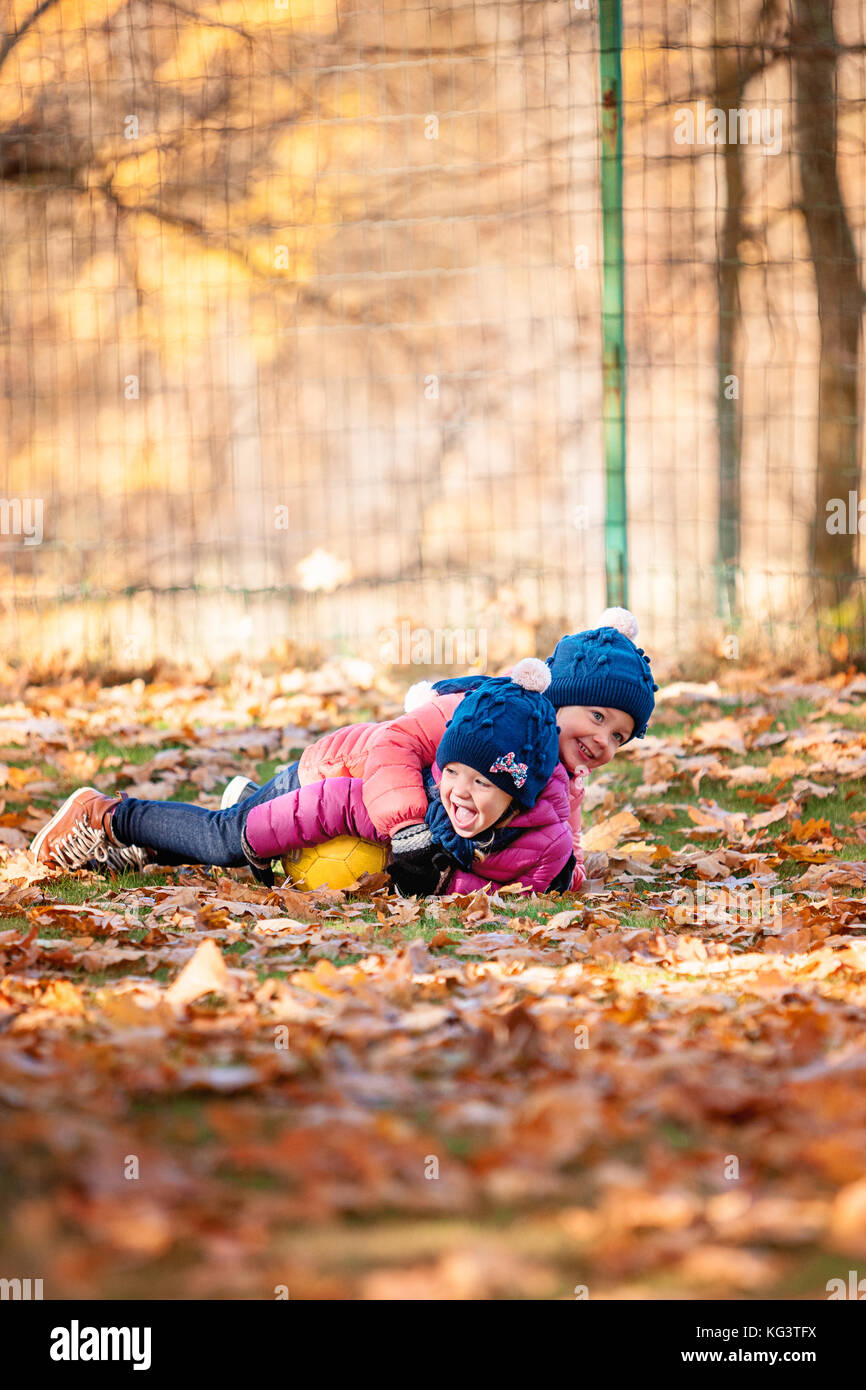 Le due piccole bambine bambino giocando in foglie di autunno Foto Stock