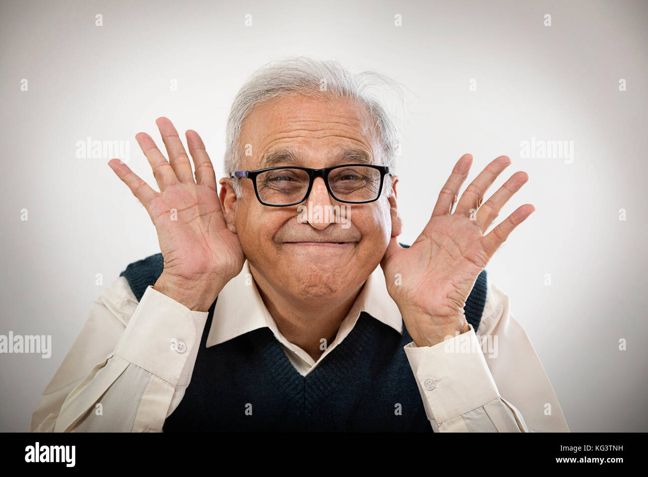 Il vecchio uomo rendere divertente faccia con le sue mani in orecchie Foto Stock