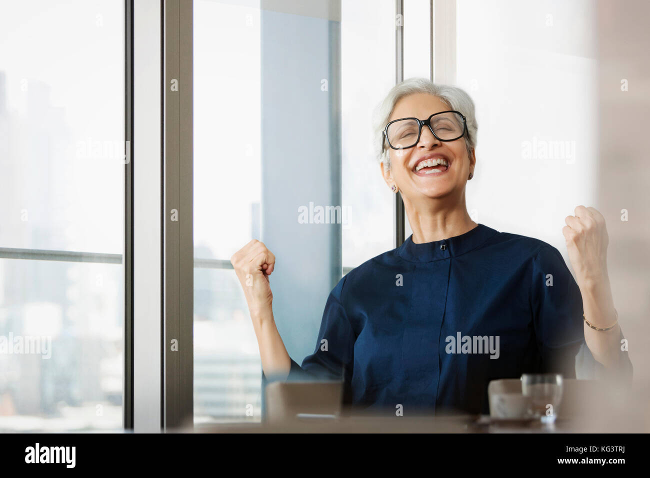 Senior sorridente donna che indossa occhiali tifo con mano a suon di pugni Foto Stock