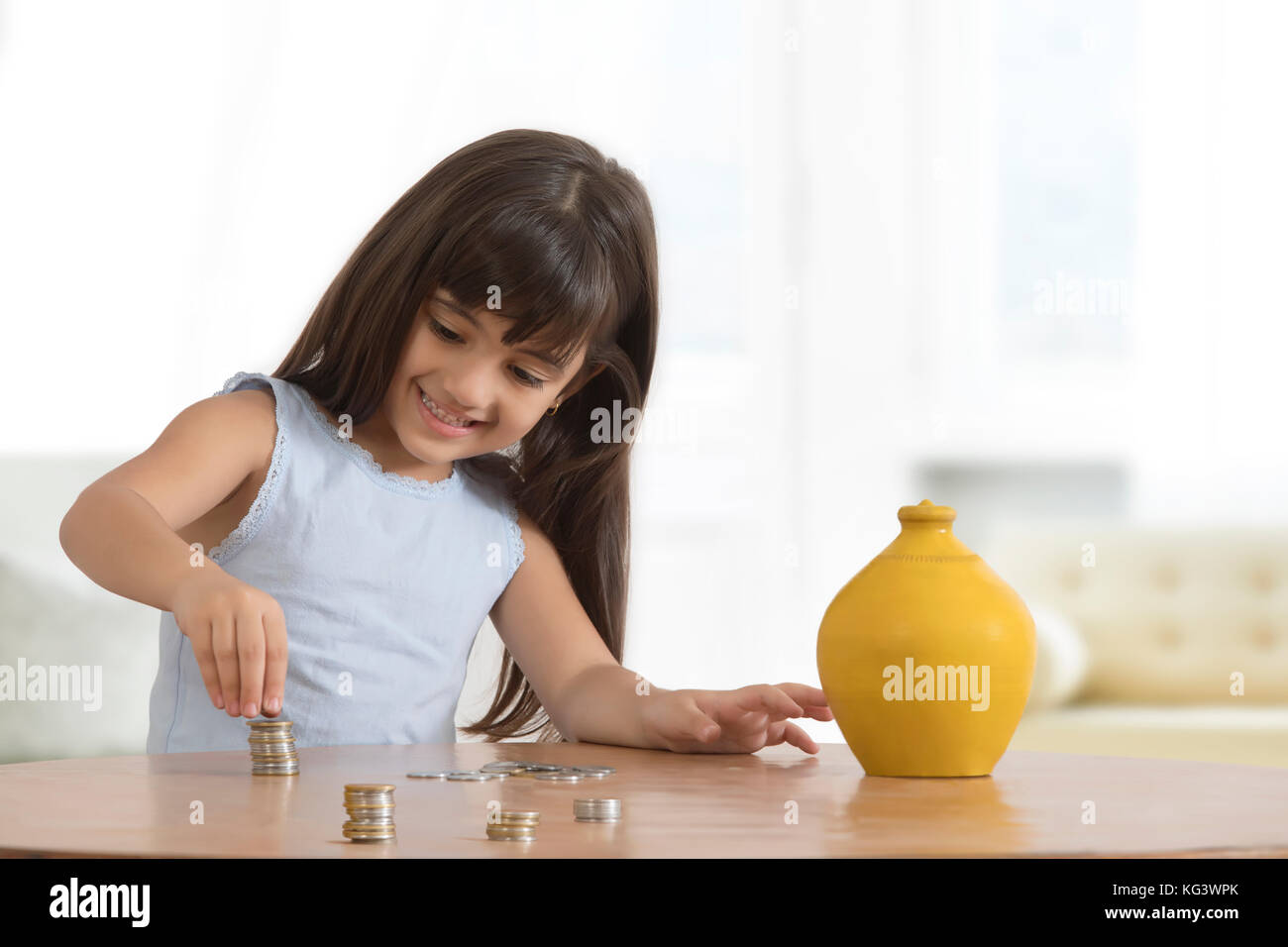 Ragazza sorridente disponendo le monete sul tavolo Foto Stock