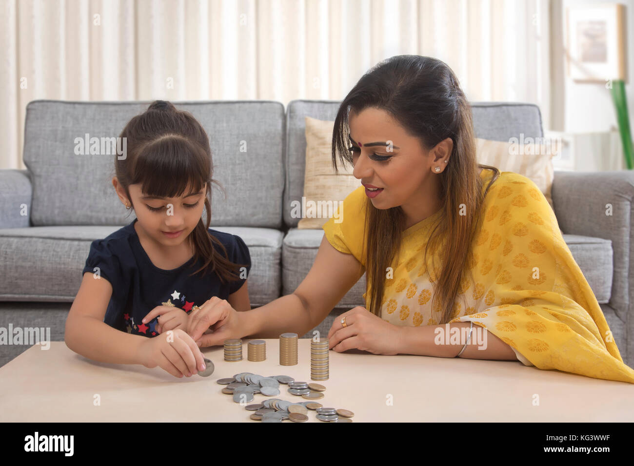 Madre e figlia di monete di stacking a casa Foto Stock