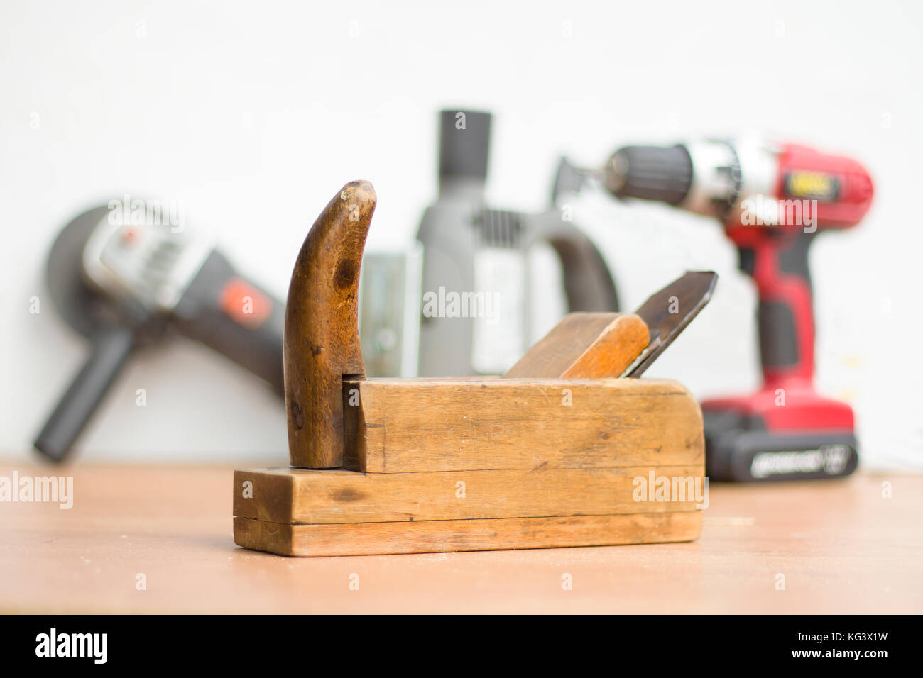 Vecchi attrezzi di falegnameria in primo piano. Nuovi strumenti di potenza in background. Vecchio falegname falegnameria in primo piano. Smerigliatrice angolare, Seghetto da traforo e screwdri Foto Stock