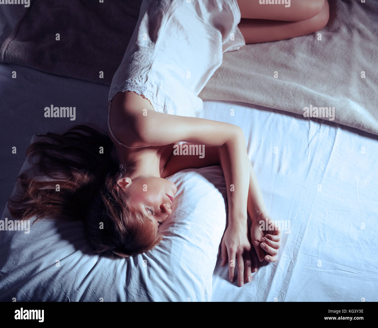 Giovane donna sdraiata lonely in letto, intenzionalmente tonica. Foto Stock