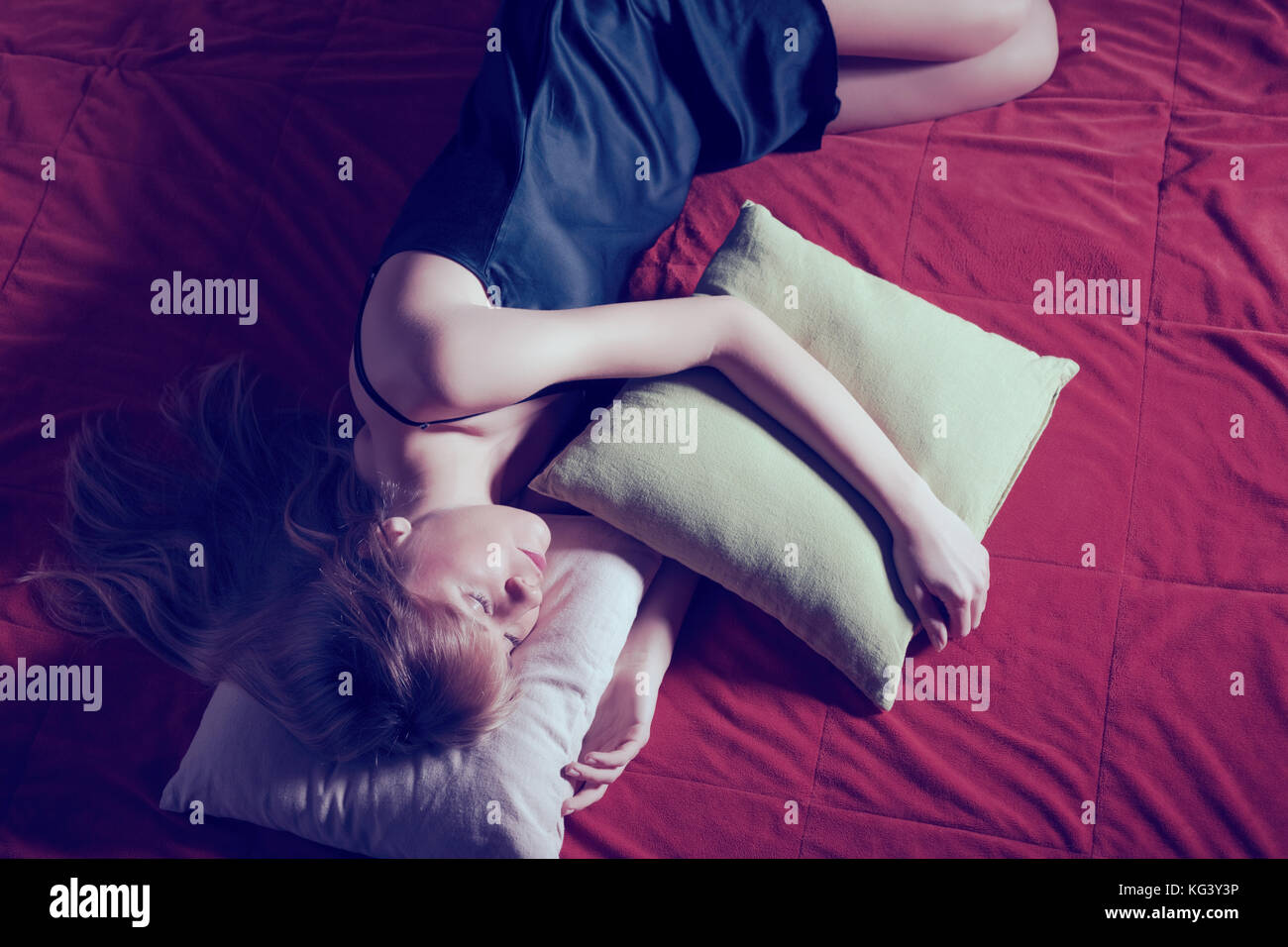 Giovane donna sdraiata lonely in letto, intenzionalmente tonica. Foto Stock