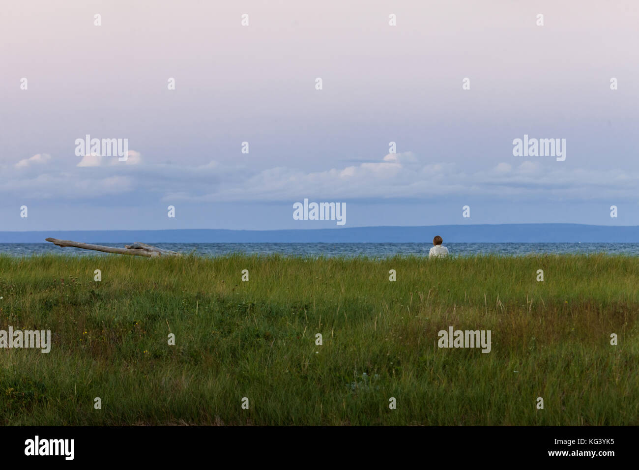 Antigonish County, Canada - 28 agosto 2017: una donna si siede e si gode della vista lungo Nova Scotia del nord della costa al tramonto. Foto Stock