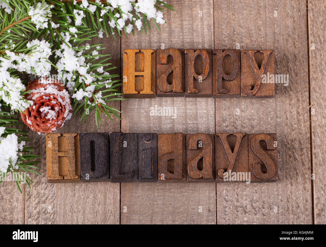 Vacanze felici del testo su una superficie in legno con snowy albero sempreverde di diramazione e di pigna Foto Stock