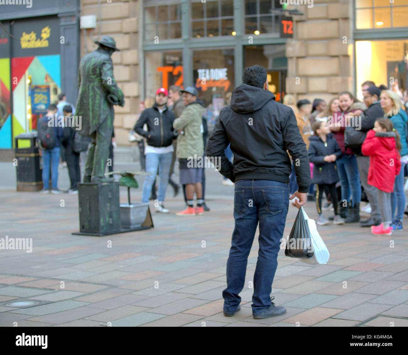 Statua vivente dell'artista di strada con uno spettatore in posa nella folla sullo stile Mile Glasgow buchanan Street vista da dietro Foto Stock