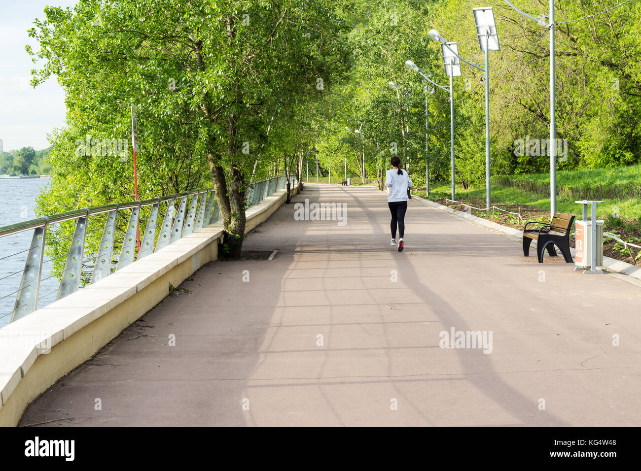 Morning jog sulla sponda del fiume nel parco della città Foto Stock