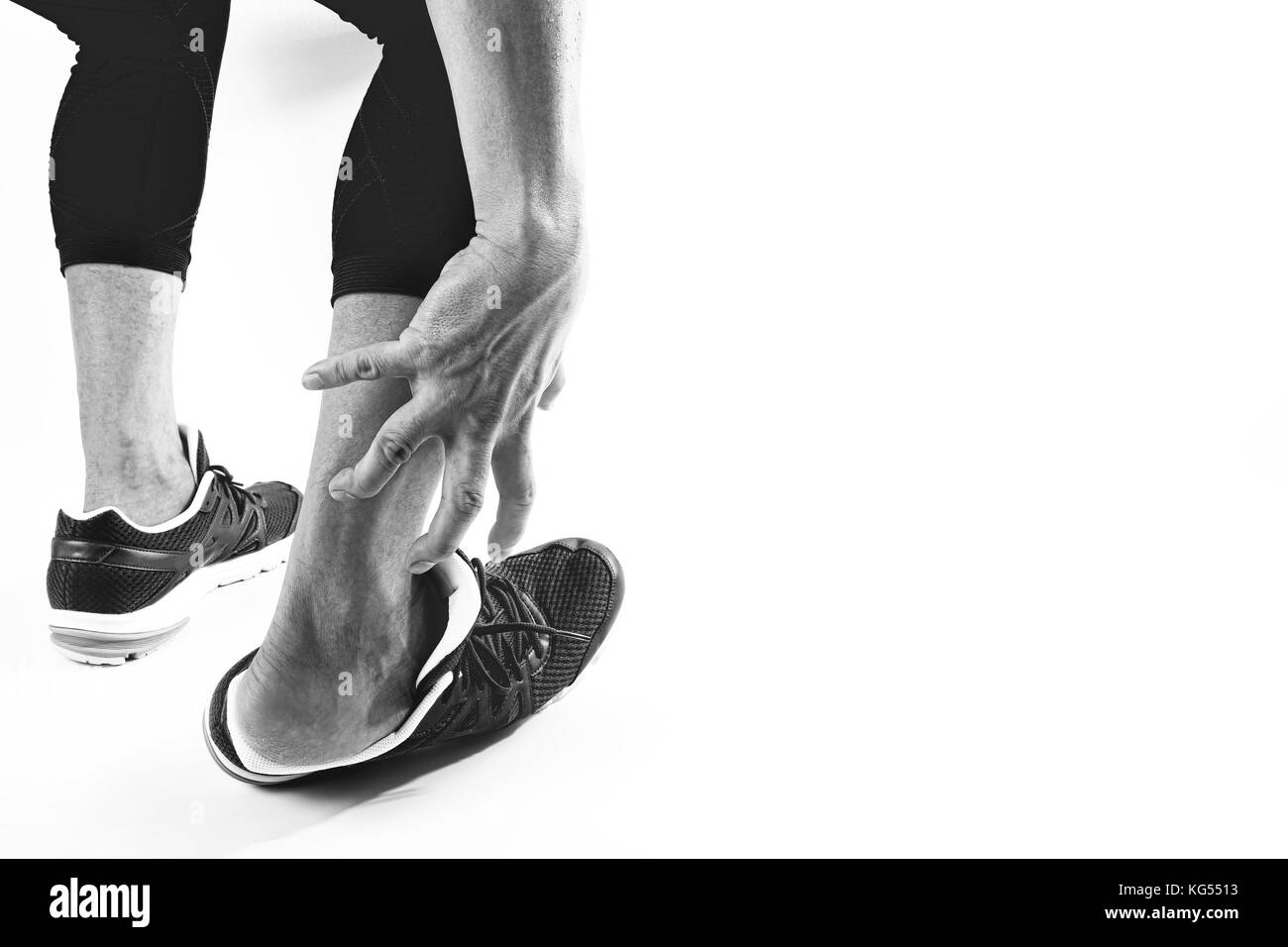 Runner sportivo tenendo la caviglia nel dolore con rotte ritorto in esecuzione congiunta di lesioni sportive e atletico uomo toccando il piede a causa di distorsione su sfondo bianco Foto Stock