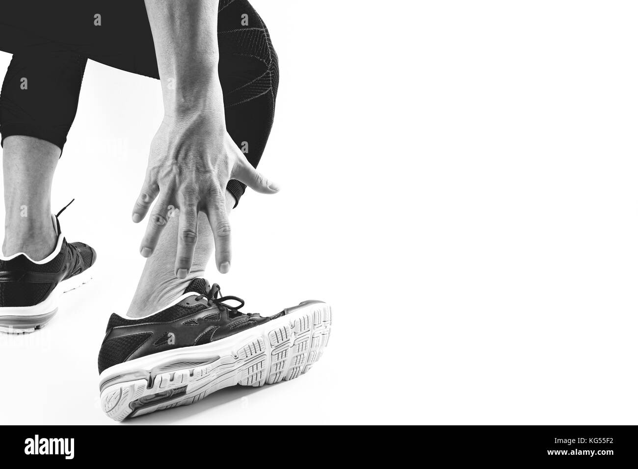 Runner sportivo tenendo la caviglia nel dolore con rotte ritorto in esecuzione congiunta di lesioni sportive e atletico uomo toccando il piede a causa di distorsione,in bianco e nero Foto Stock