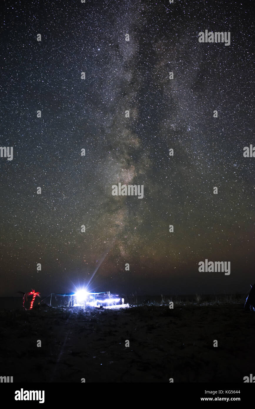 Tenda illuminata sulla spiaggia sullo sfondo di un cielo luminoso con via lattea. Foto Stock