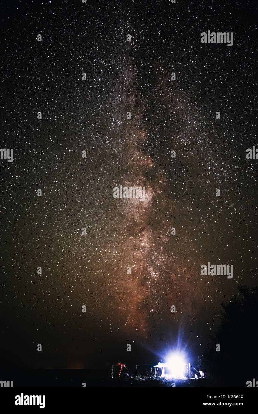 Tenda illuminata sulla spiaggia sullo sfondo di un cielo luminoso con via lattea. Foto Stock