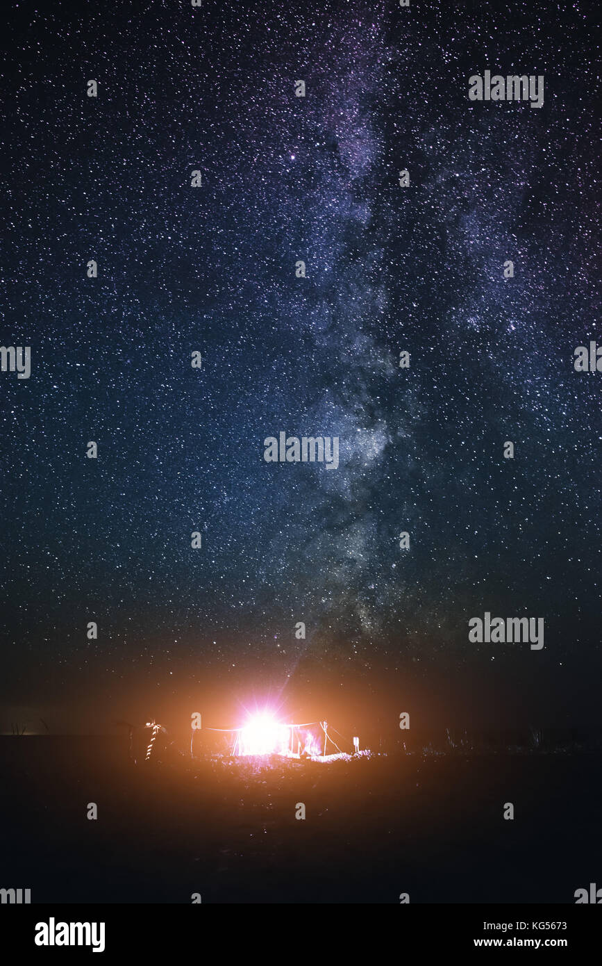 Tenda illuminata sulla spiaggia sullo sfondo di un cielo luminoso con via lattea. Foto Stock