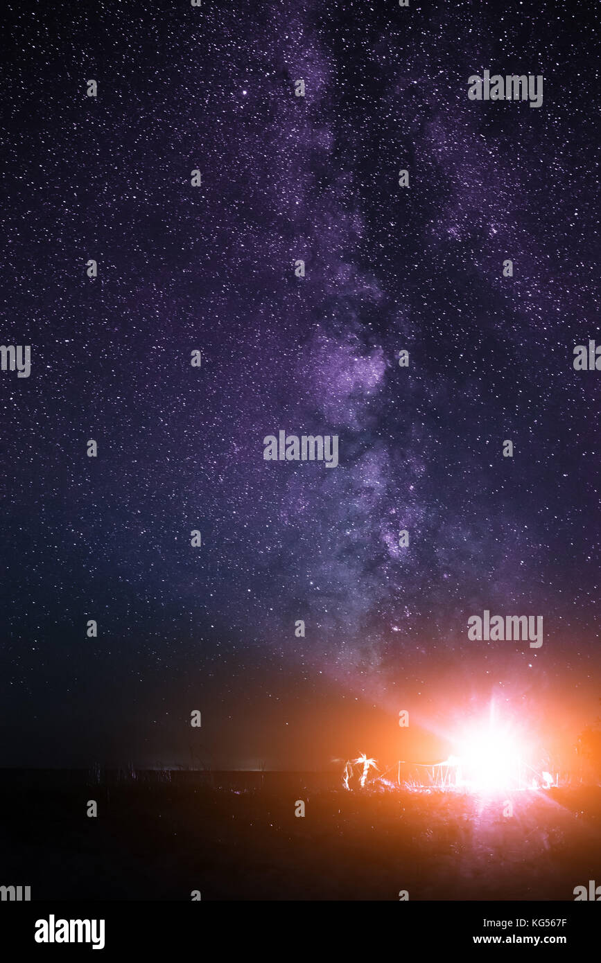Tenda illuminata sulla spiaggia sullo sfondo di un cielo luminoso con via lattea. Foto Stock