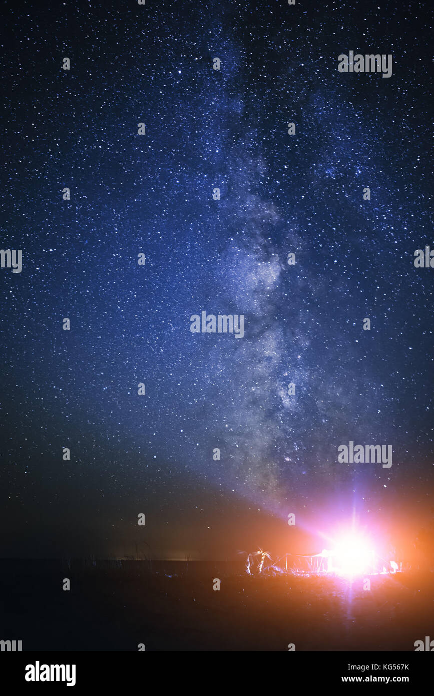 Tenda illuminata sulla spiaggia sullo sfondo di un cielo luminoso con via lattea. Foto Stock