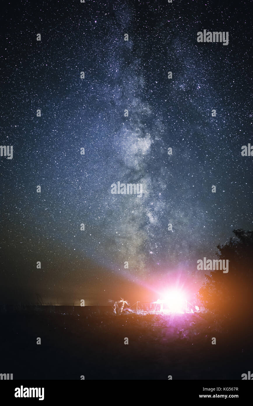 Tenda illuminata sulla spiaggia sullo sfondo di un cielo luminoso con via lattea. Foto Stock