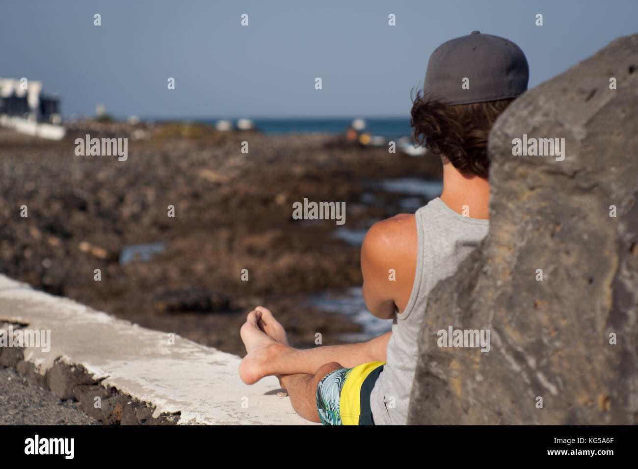 Uomo seduto looiking al mare Foto Stock