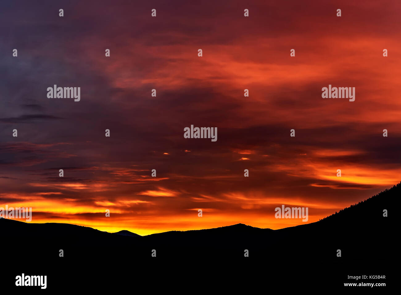 Luminose colorate sunrise in giallo, arancione, toni di blu con le nuvole, illuminata dai raggi del sole nel cielo sopra le montagne Foto Stock