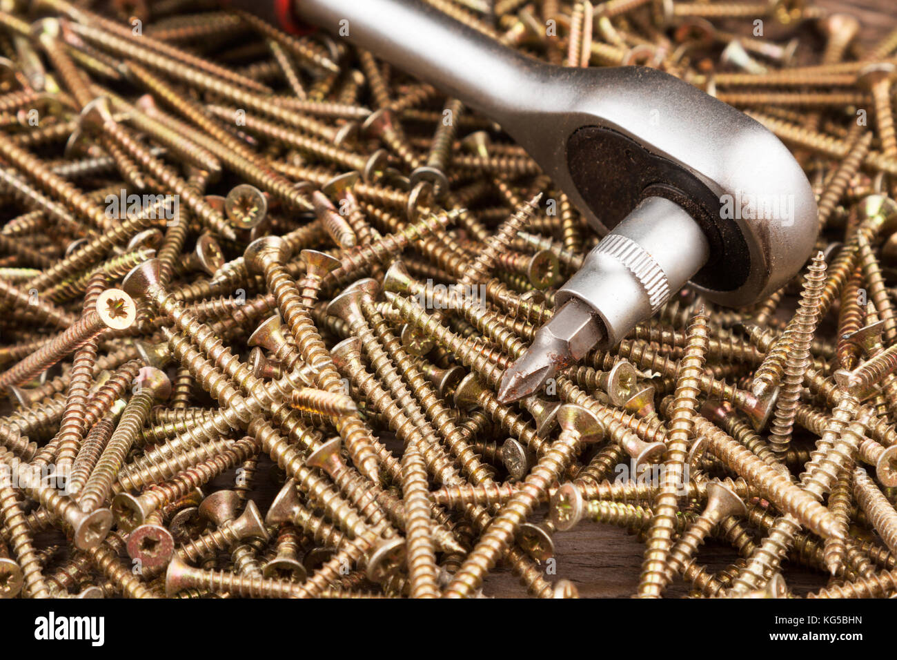 Chiave con testa di avvitamento giace contro lo sfondo delle viti. Close-up costruzione e riparazione Foto Stock