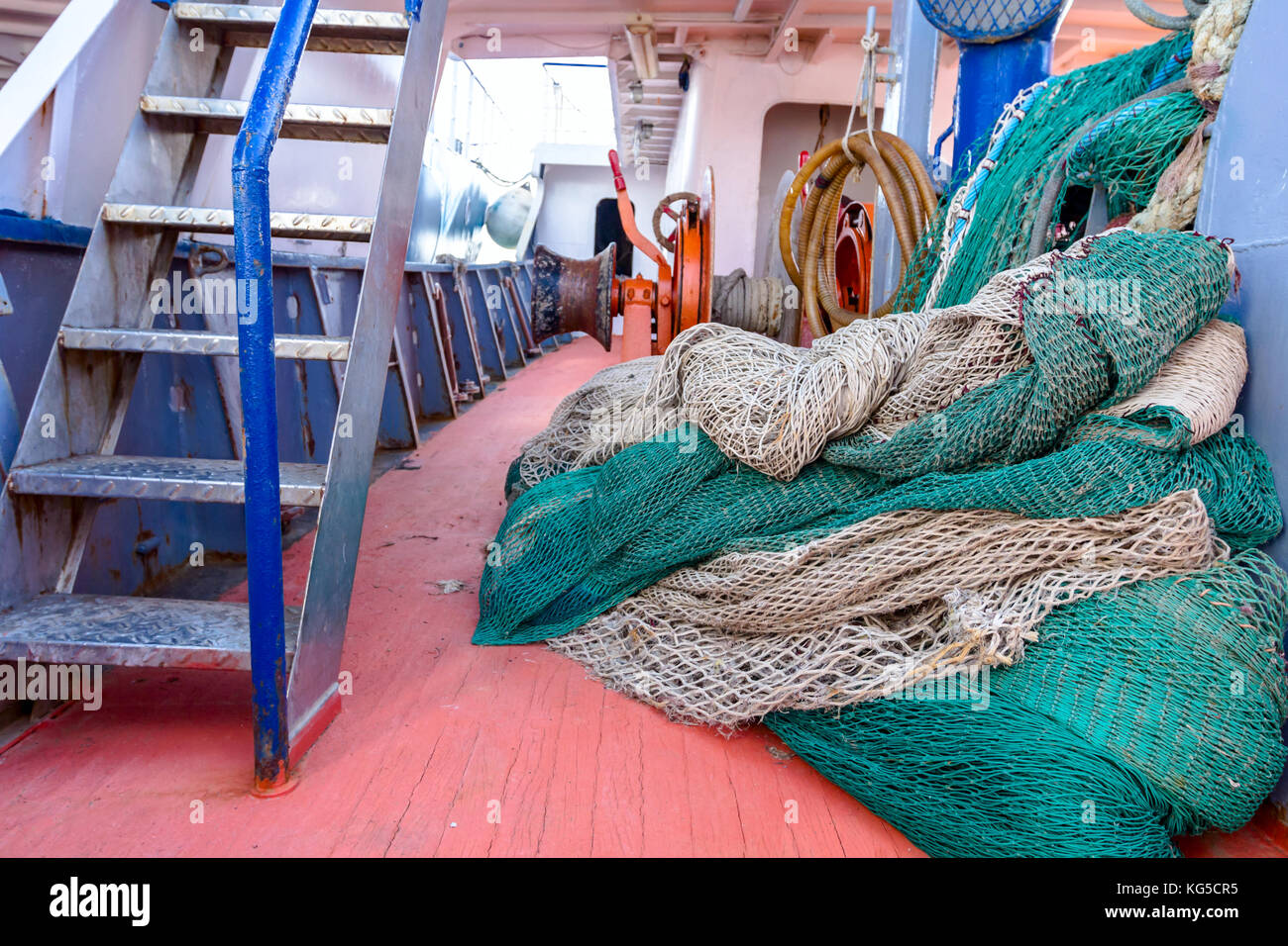 Pila di pesca commerciale net, attrezzature per la pesca in mare aperto su un ampio ponte della nave. Foto Stock