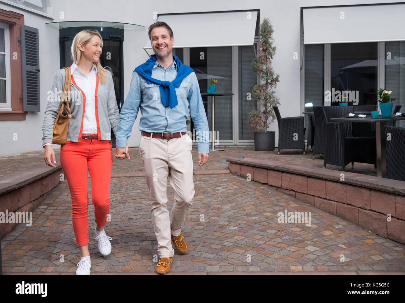 L uomo e la donna camminare mano nella mano verso la telecamera, sorridente Foto Stock