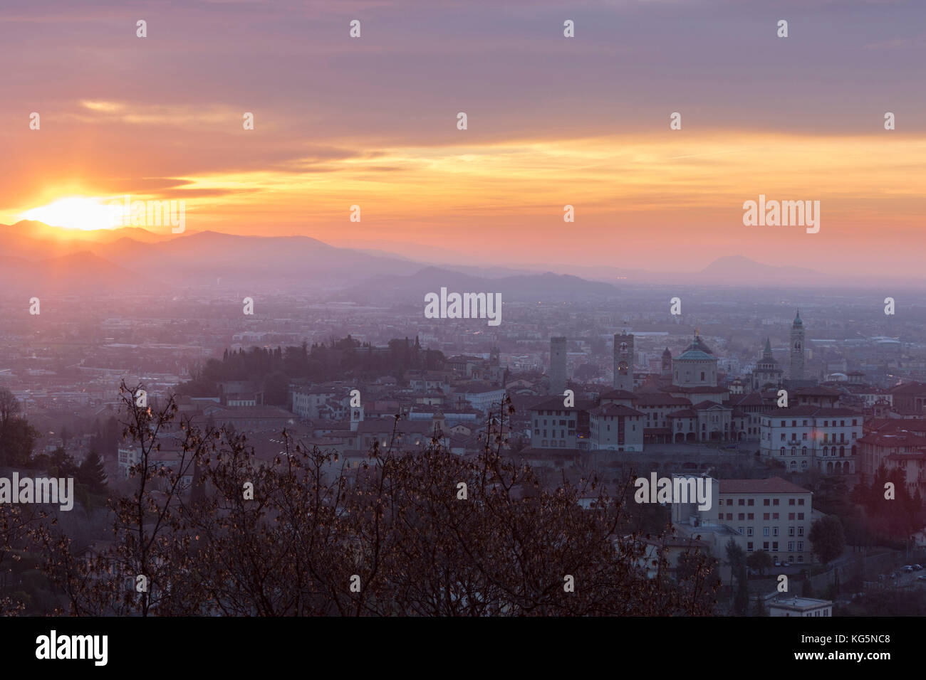 Vista della città vecchia medievale chiamato Città Alta sulla collina incorniciato da Fiery orange sky all'alba Bergamo Lombardia Italia Europa Foto Stock