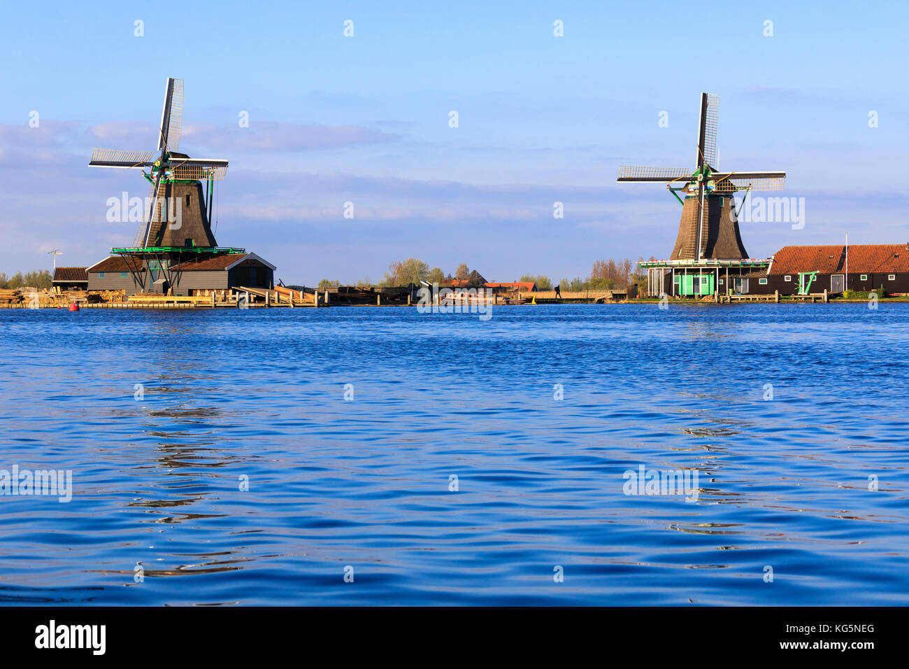 Mulini a vento tipico riflesso nell'acqua blu del fiume Zaan in primavera a Zaanse Schans Olanda settentrionale dei Paesi Bassi in Europa Foto Stock