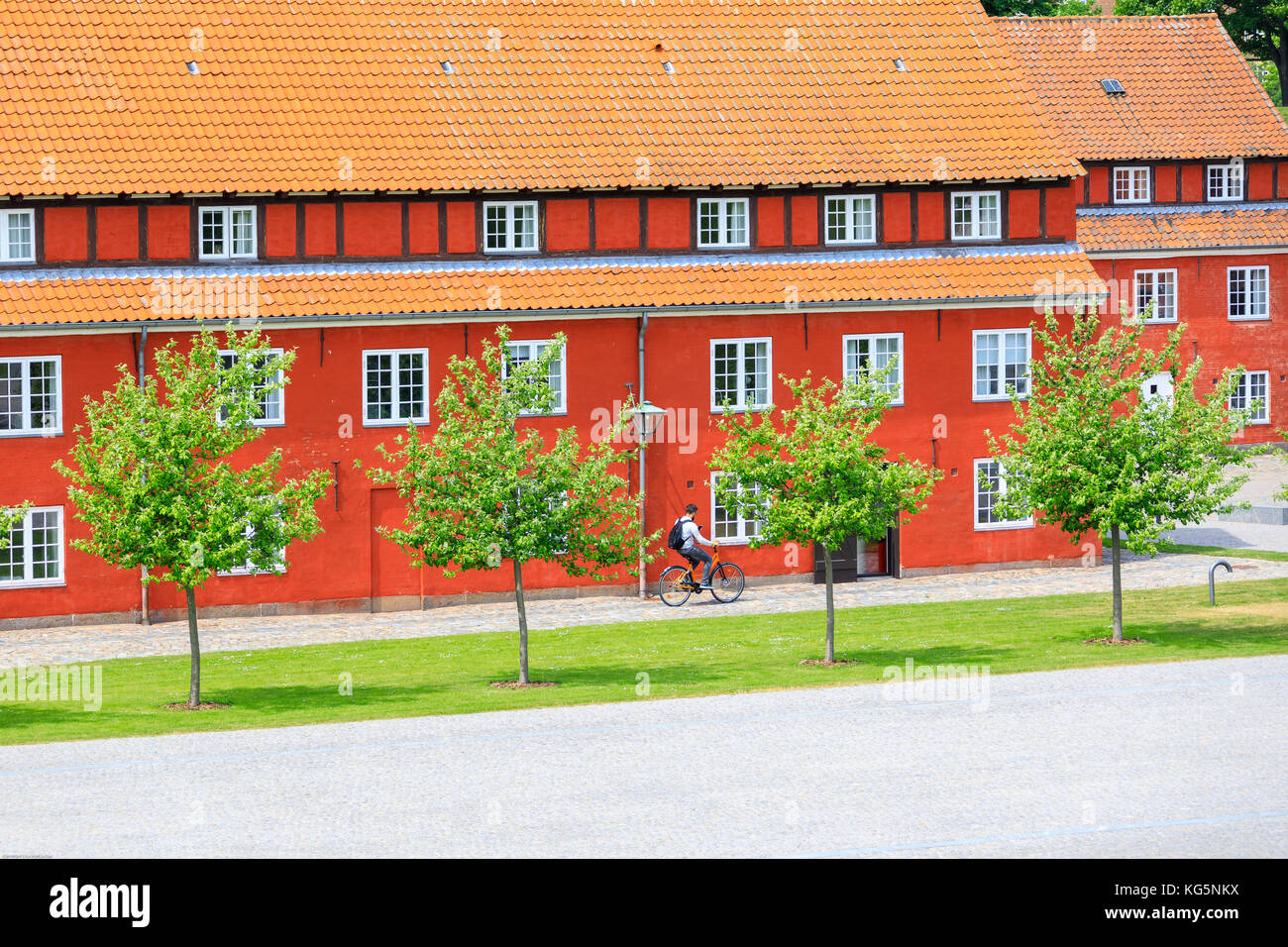 In bicicletta tra le case rosse, la cittadella (kastellet), Copenhagen, Danimarca Foto Stock