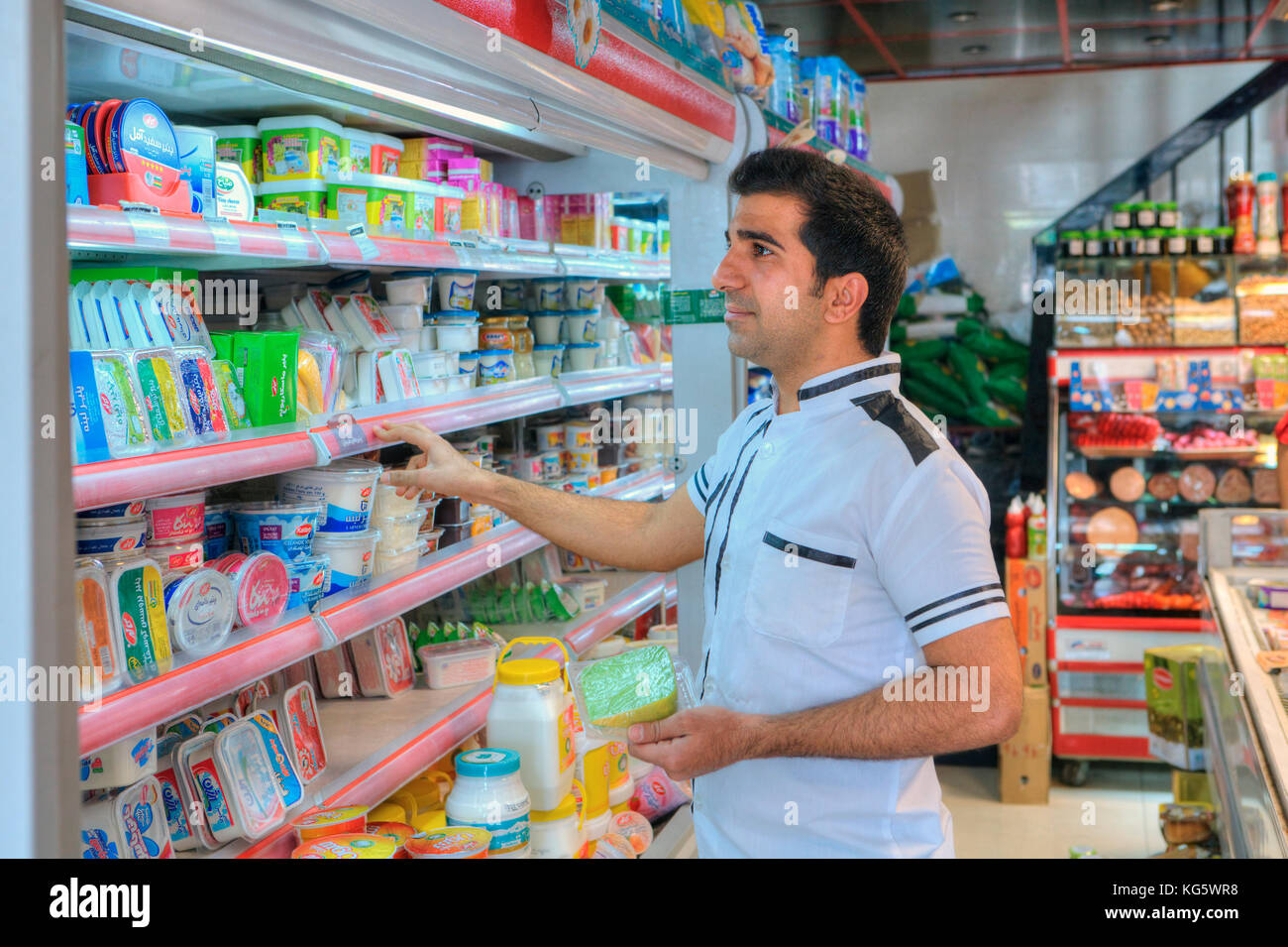 Far provincia, Shiraz, Iran - 20 aprile, 2017: uno sconosciuto di mezza età iraniano che considera gli elementi di generi alimentari sul negozio di alimentari ripiano. Foto Stock