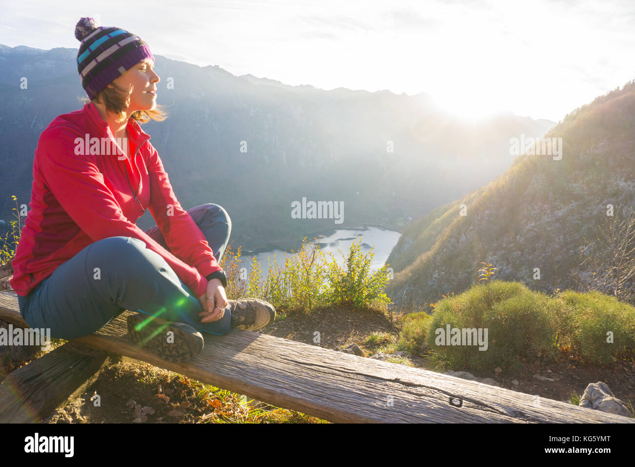 Giovane donna seduta sul ramo sul punto di vista, per rilassarsi dopo le escursioni e guardando il lago di Bohinj, slovenia Foto Stock