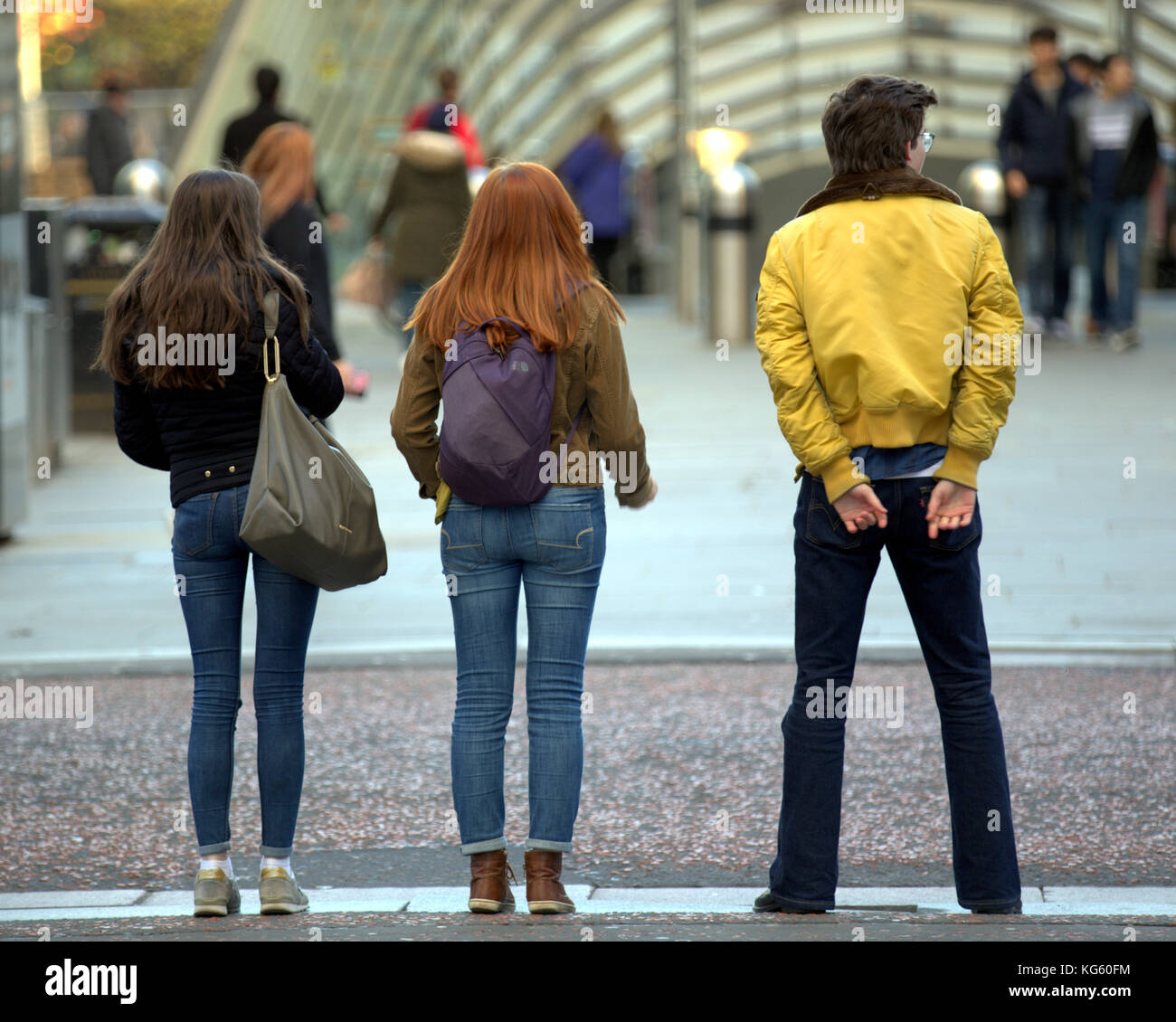 Giornata di sole a Glasgow e la gente del posto per le strade moda giovane visto da dietro Foto Stock