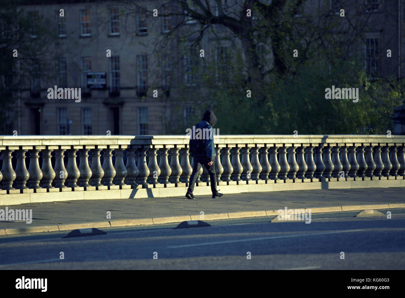 Adolescente incappucciati camminare da solo bassa sera sun prospettiva vista da dietro Foto Stock