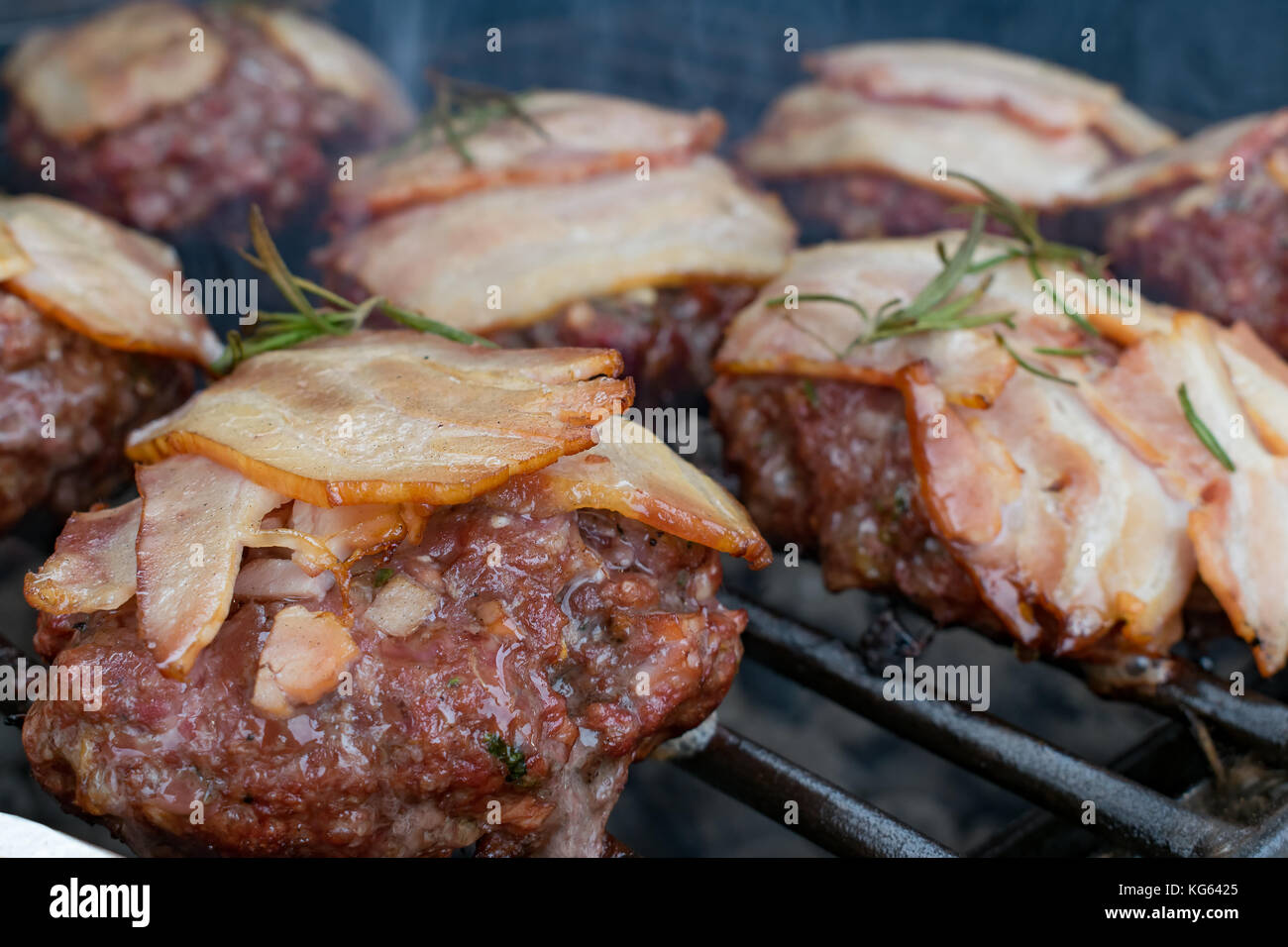 Hamburger con pancetta essendo grigliate sul barbecue Foto Stock