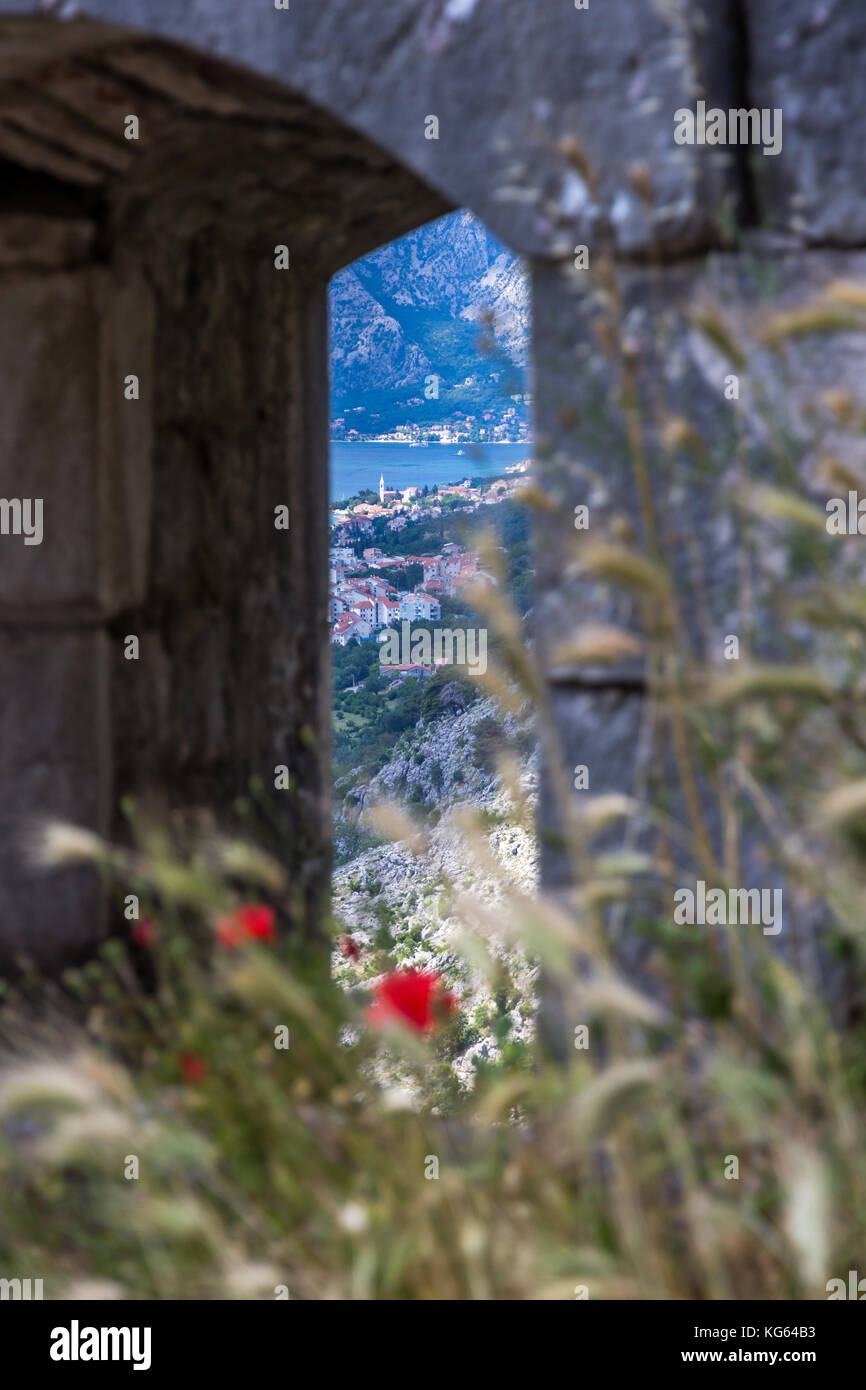 Guardando attraverso spesse mura difensive in pietra fino a Perast e al Golfo di Cattaro dalle rovine della Fortezza sulle mura della città Vecchia di Cattaro, Montrnegro Foto Stock