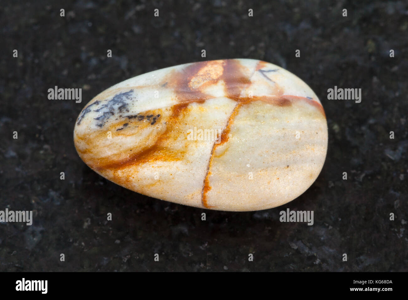 Le riprese in modalità macro di minerale naturale campione di roccia - lucidato immagine pietra di diaspro sul granito scuro sfondo dalla Cina Foto Stock