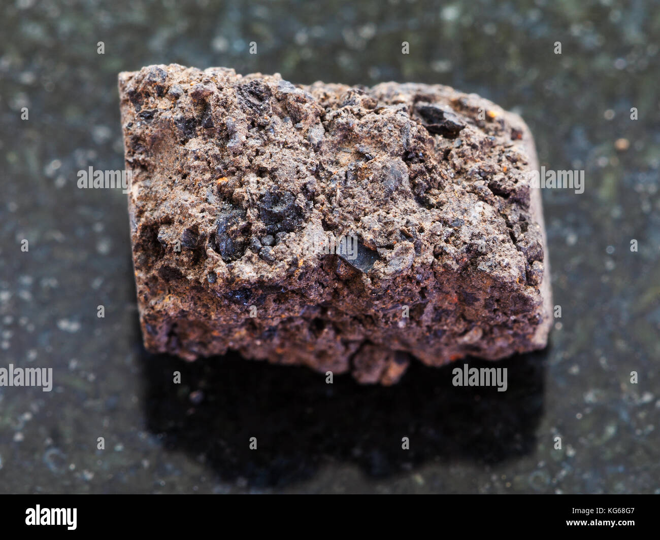 Le riprese in modalità macro di minerale naturale campione di roccia - torba irregolare turf sulla pietra di granito scuro dello sfondo Foto Stock