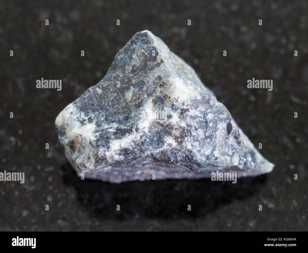 Le riprese in modalità macro di minerale naturale campione di roccia - stibnite ruvida (antimonite) minerale sul granito scuro dello sfondo Foto Stock
