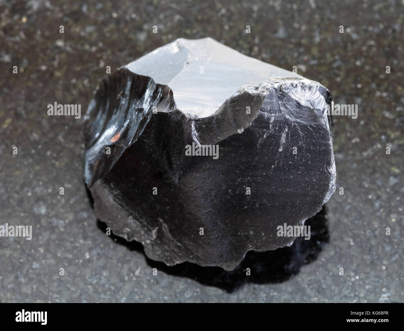 Le riprese in modalità macro di minerale naturale campione di roccia - materie ossidiana (vetro vulcanico) crystal sul granito scuro dello sfondo Foto Stock