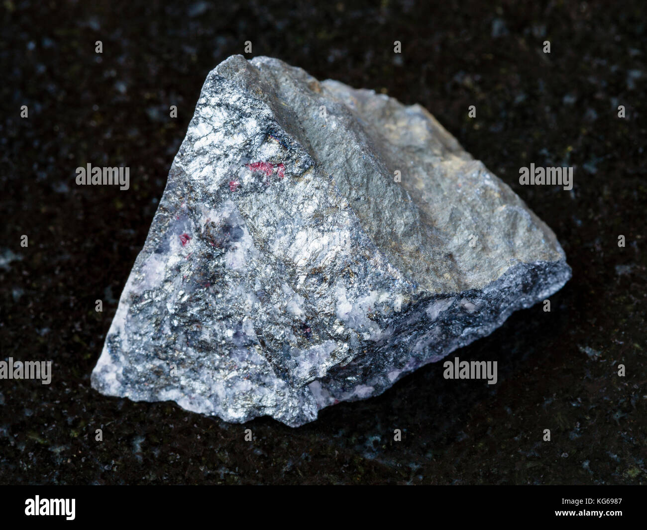 Le riprese in modalità macro di minerale naturale campione di roccia - antimonite ruvida sulla pietra di granito scuro dello sfondo chauvay dal distretto di Kirghizistan Foto Stock