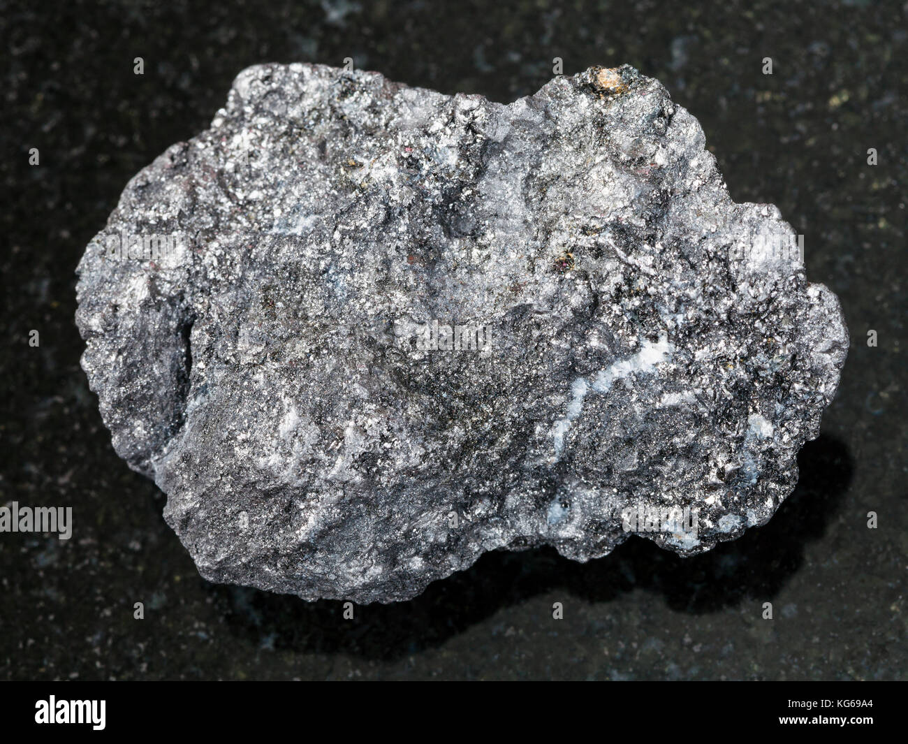 Le riprese in modalità macro di minerale naturale campione di roccia - grafite ruvida sulla pietra di granito scuro lo sfondo da bogotol regione orientale di sayan montagne, Russ Foto Stock