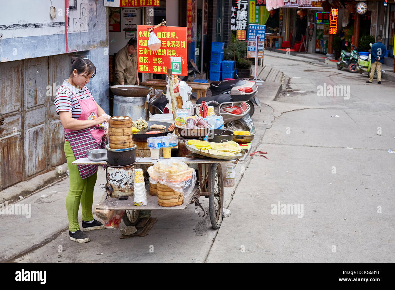 Lijiang, Yunnan, Cina - 27 Settembre 2017: Donna prepara e vende il cibo a colazione da bancarella di strada. Il pagamento tramite il codice QR diventa molto comune in chi Foto Stock