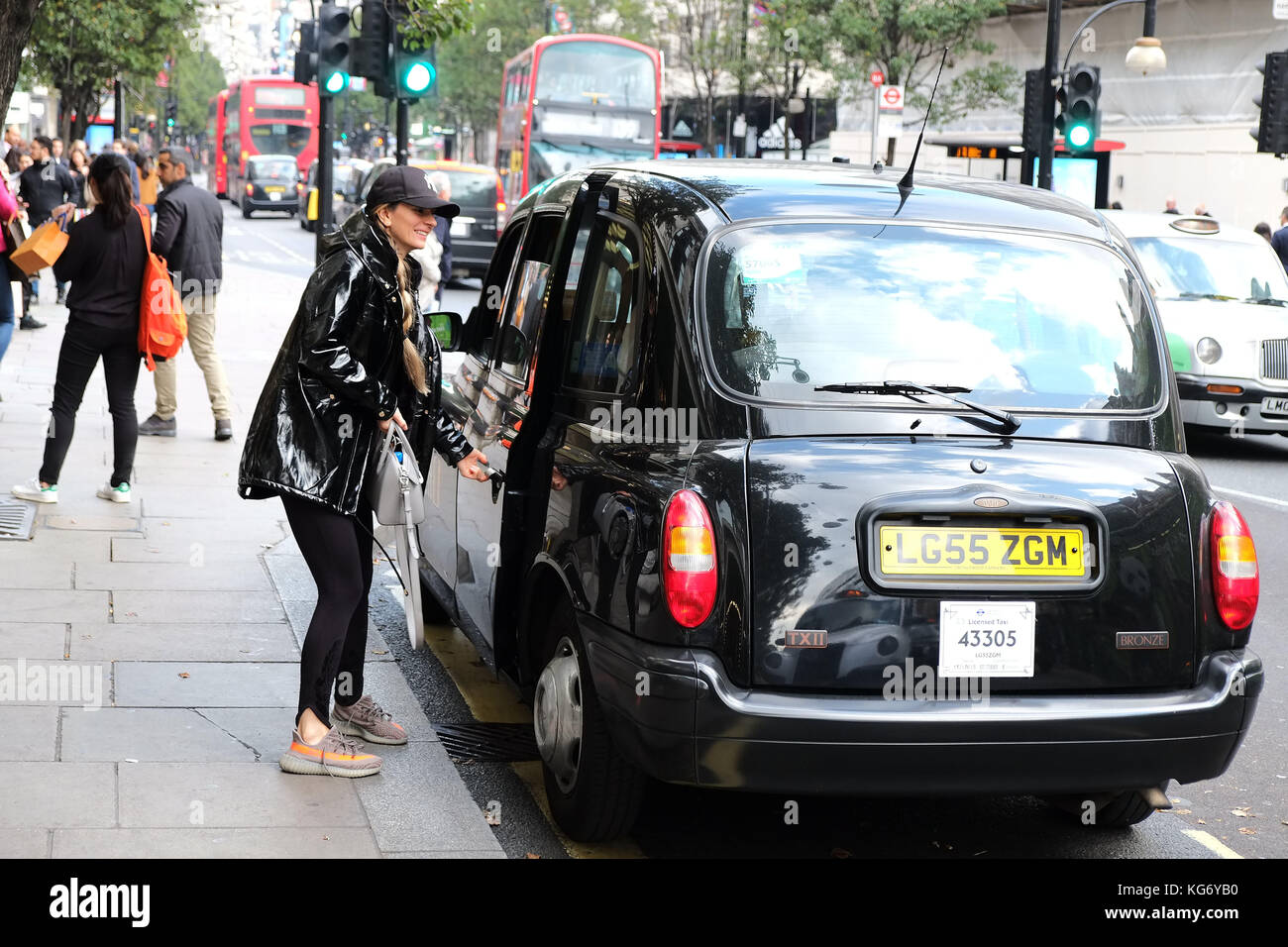 Hailing un tradizionale taxi nero a Londra al di fuori di Selfridges su Oxford Street Central London UK Foto Stock