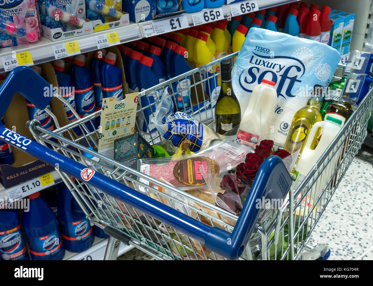 Un carrello della spesa pieno di negozi di generi alimentari nel supermercato nella famiglia di prodotti per la pulizia corsia, Scotland, Regno Unito Foto Stock