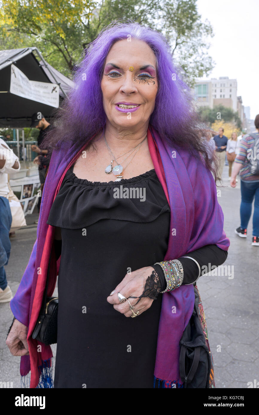 Una donna nel suo anni sessanta con capelli viola, insolito trucco per occhi e un look giovanile in Lower Manhattan, New York City. Foto Stock