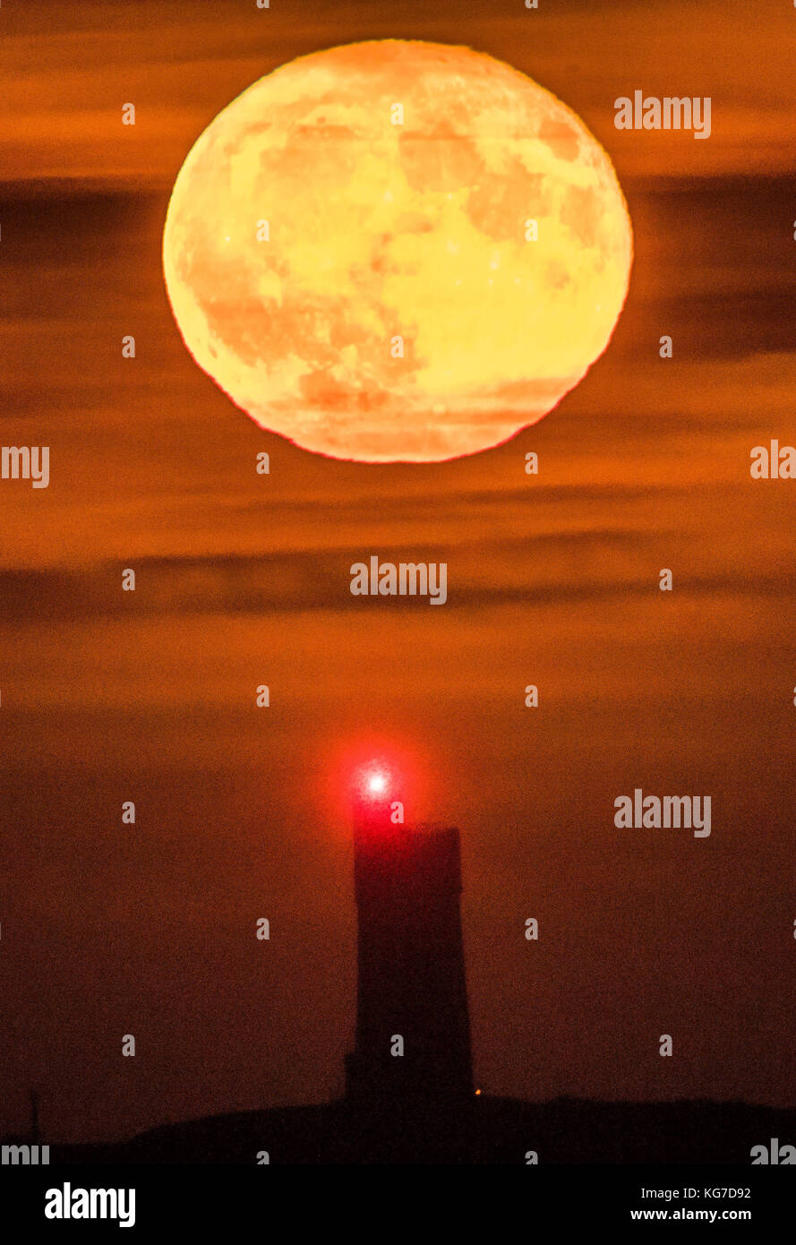 Una luna piena di novembre, che è conosciuta come la Luna del castoro secondo i nativi americani del nord, sorge dietro la Victoria Tower di grado II sulla cima di Castle Hill a Huddersfield. Foto Stock